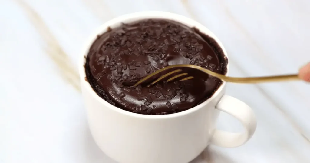 Indulgent Oreo mug cake topped with creamy whipped cream, a delightful treat in a mug